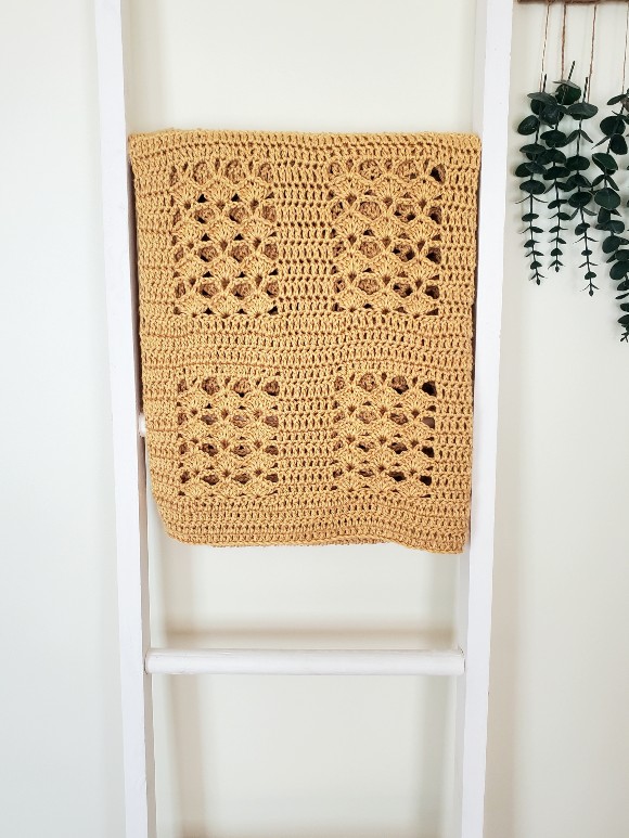 photo of a crochet blanket on a ladder